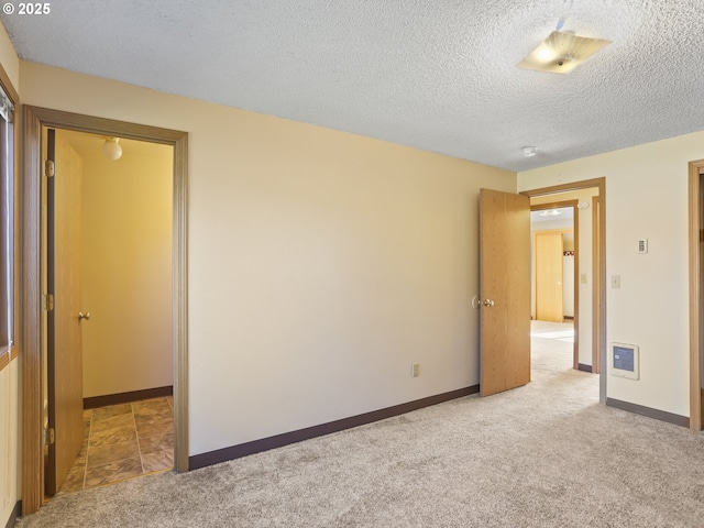 unfurnished bedroom featuring a textured ceiling, baseboards, and carpet