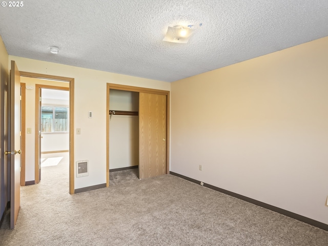 unfurnished bedroom featuring a closet, a textured ceiling, baseboards, and carpet