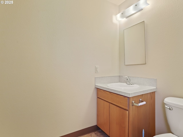 bathroom with toilet, vanity, and baseboards