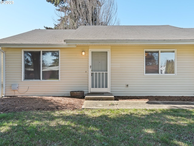 view of front facade with roof with shingles and a front yard