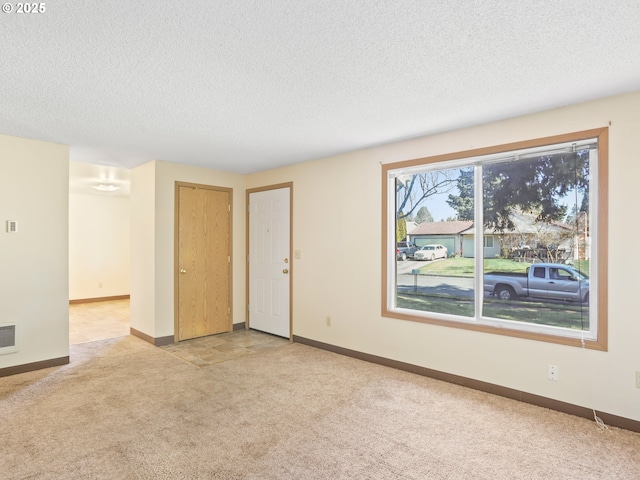 spare room featuring carpet flooring, a textured ceiling, and baseboards