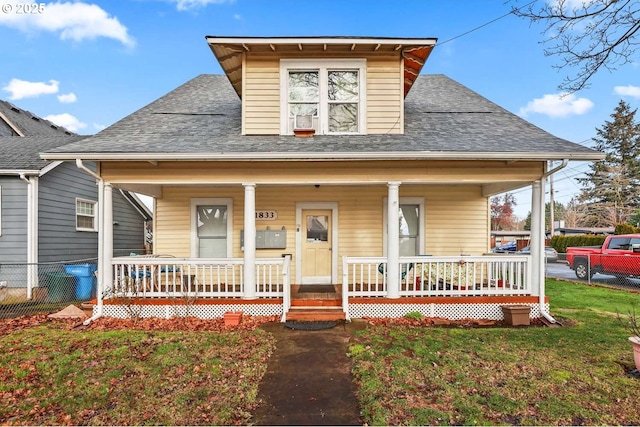 bungalow-style house with a porch, roof with shingles, and a front lawn