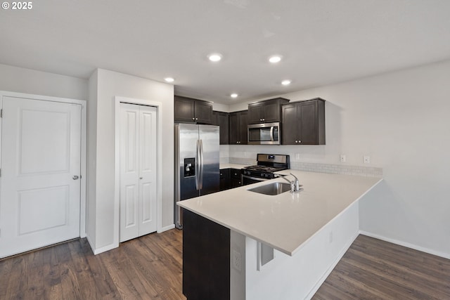 kitchen with sink, dark wood-type flooring, kitchen peninsula, and appliances with stainless steel finishes