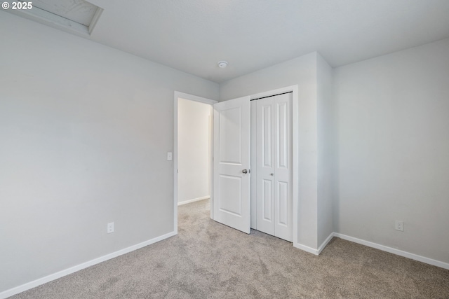 unfurnished bedroom with light colored carpet and a closet