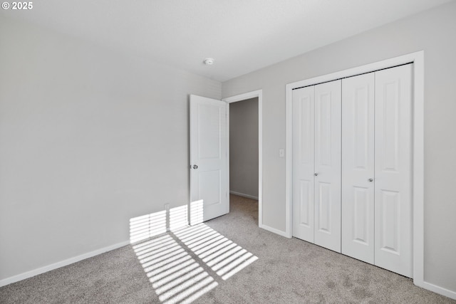 unfurnished bedroom featuring light colored carpet and a closet