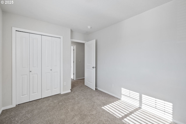 unfurnished bedroom featuring light carpet and a closet