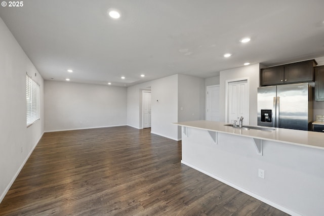 kitchen featuring sink, dark hardwood / wood-style flooring, a kitchen bar, stainless steel refrigerator with ice dispenser, and dark brown cabinets