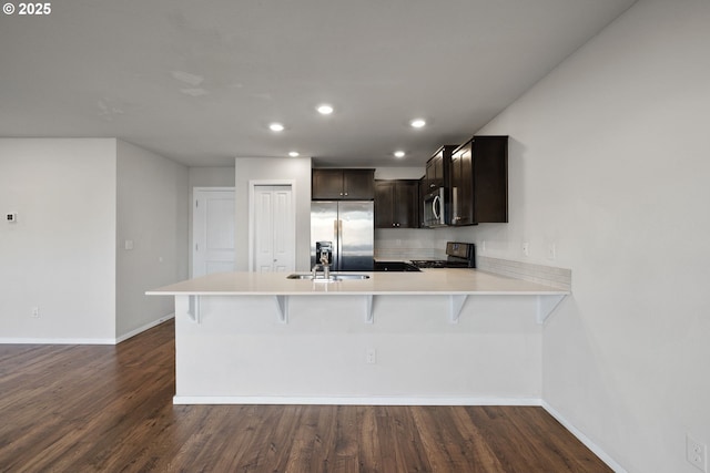 kitchen featuring a kitchen bar, sink, kitchen peninsula, and appliances with stainless steel finishes