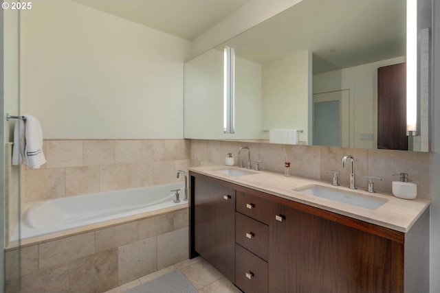 bathroom with tile patterned flooring, a relaxing tiled tub, and vanity