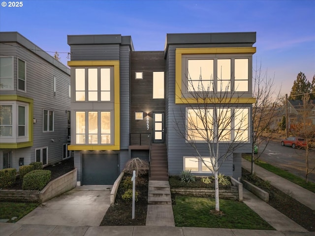 contemporary home with concrete driveway, stairway, and an attached garage