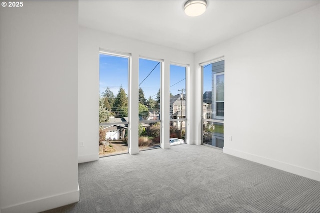 carpeted spare room featuring baseboards