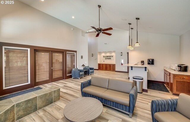 living room featuring ceiling fan, light wood-type flooring, french doors, and high vaulted ceiling