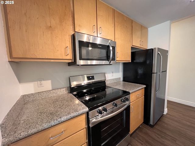 kitchen featuring dark wood-type flooring, stone countertops, and stainless steel appliances