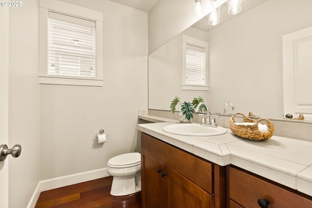 bathroom with toilet, vanity, and hardwood / wood-style floors