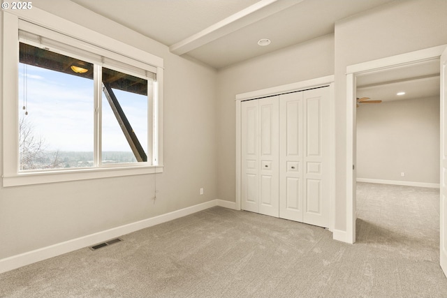 unfurnished bedroom featuring light colored carpet and a closet