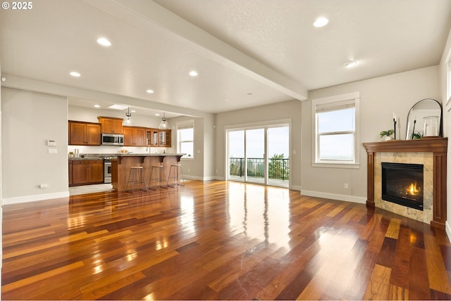 living room with dark wood-type flooring, a tile fireplace, and beamed ceiling