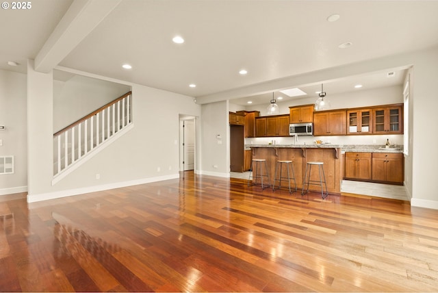 kitchen with a breakfast bar, beamed ceiling, light hardwood / wood-style flooring, and a kitchen island