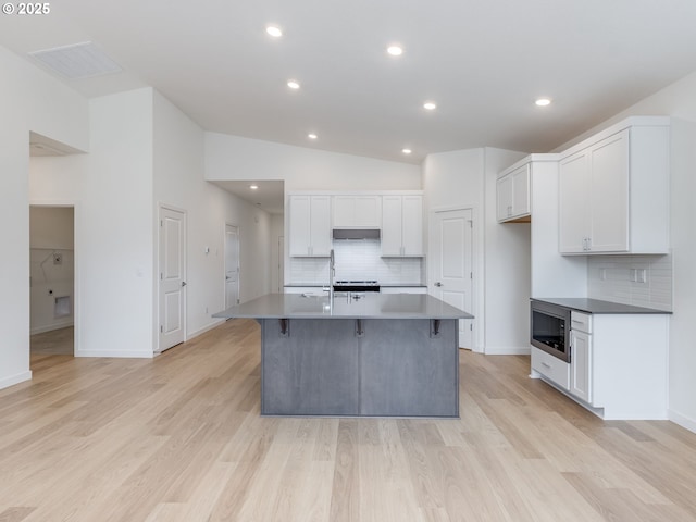 356 NW 29th Way, Battle Ground, WA 98604 - kitchen featuring decorative backsplash, white cabinetry, vaulted ceiling, light wood-style floors, and a breakfast bar area