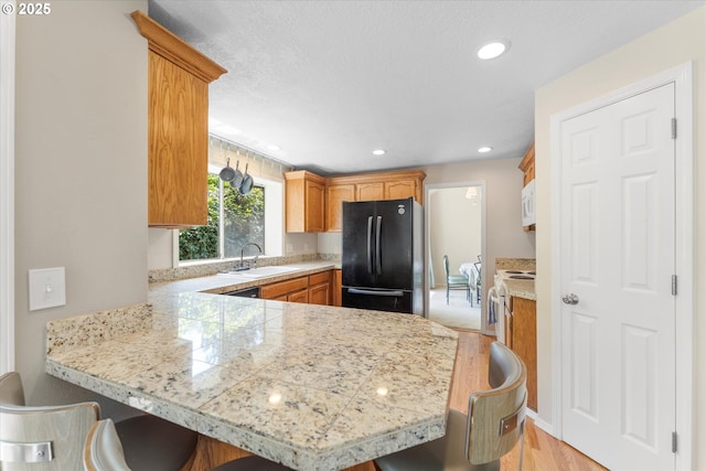 20198 SW Tillamook Ct, Tualatin, OR 97062 - kitchen featuring white appliances, a peninsula, a breakfast bar, tile countertops, and recessed lighting