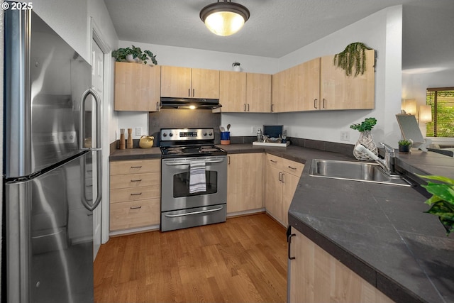 1535 SW Clay St Unit 238, Portland, OR 97201 - kitchen featuring appliances with stainless steel finishes, light brown cabinets, a sink, dark countertops, and under cabinet range hood