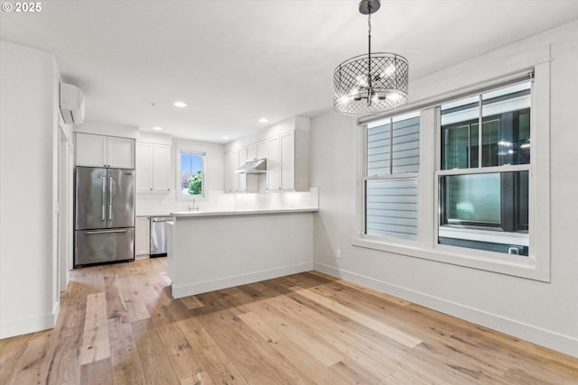kitchen with appliances with stainless steel finishes, under cabinet range hood, white cabinetry, a chandelier, and baseboards
