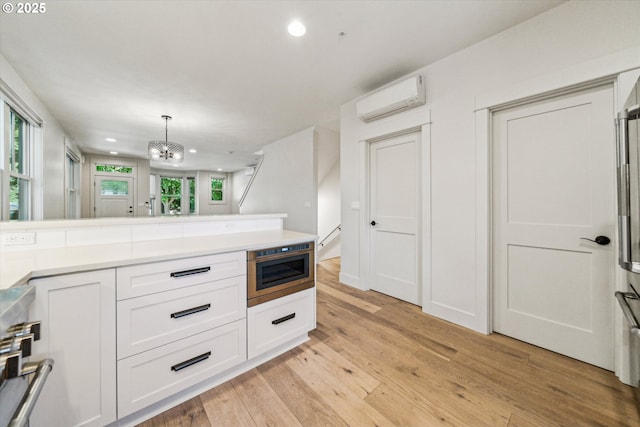 kitchen featuring a wall mounted AC, recessed lighting, white cabinets, light wood finished floors, and light countertops