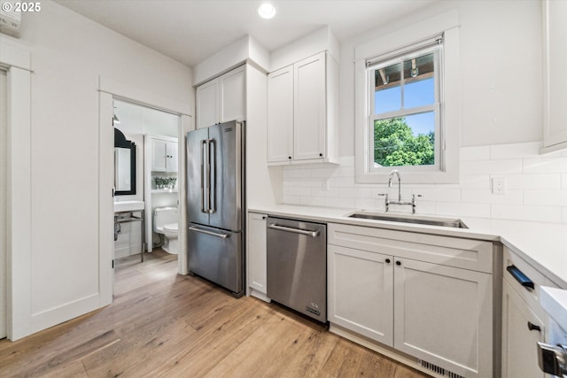 kitchen featuring appliances with stainless steel finishes, a sink, tasteful backsplash, light countertops, and recessed lighting