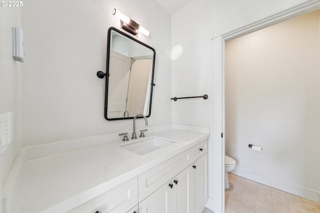 bathroom with toilet, vanity, and baseboards