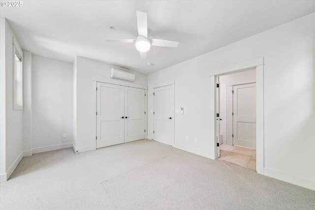 unfurnished bedroom with a wall mounted air conditioner, light carpet, baseboards, connected bathroom, and a ceiling fan
