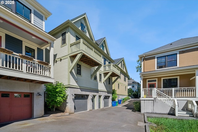 view of home's exterior featuring an attached garage, a balcony, a residential view, driveway, and a porch
