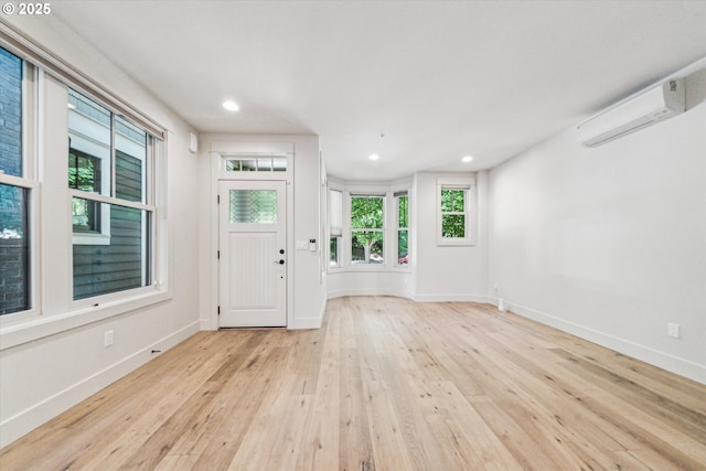 entrance foyer with hardwood / wood-style floors, baseboards, a wall unit AC, and recessed lighting