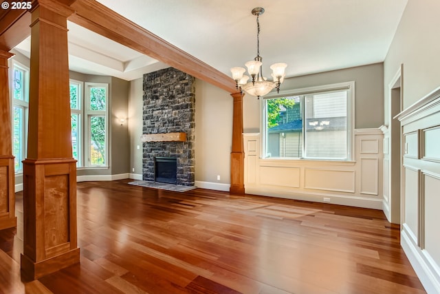 14702 SE Badger Creek Rd, Happy Valley, OR 97086 - unfurnished living room featuring decorative columns, wood finished floors, a chandelier, a stone fireplace, and a decorative wall