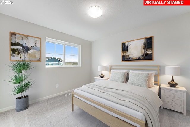 bedroom featuring light carpet, a textured ceiling, and baseboards