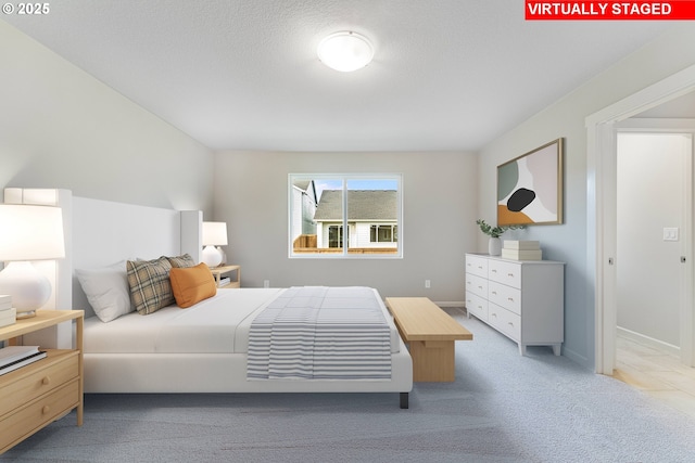 bedroom featuring light carpet, a textured ceiling, and baseboards