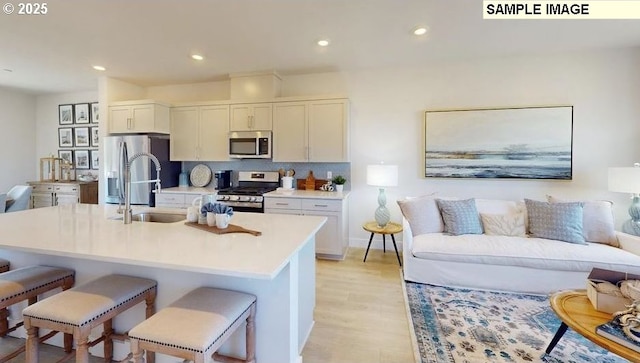 kitchen featuring a breakfast bar area, recessed lighting, a sink, appliances with stainless steel finishes, and open floor plan