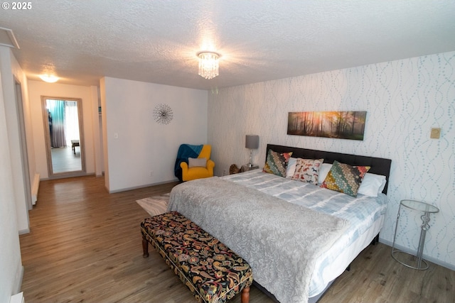 1896 W Park Dr, Florence, OR 97439 - bedroom with wallpapered walls, wood finished floors, a textured ceiling, baseboards, and an accent wall