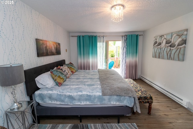 1896 W Park Dr, Florence, OR 97439 - bedroom featuring a baseboard heating unit, wallpapered walls, wood finished floors, a textured ceiling, and access to outside