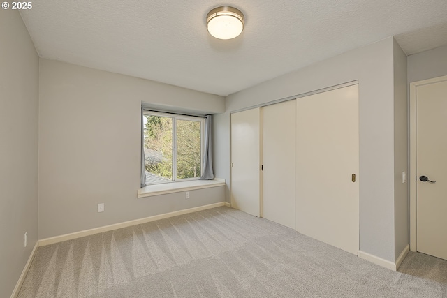 unfurnished bedroom featuring a closet, baseboards, carpet, and a textured ceiling