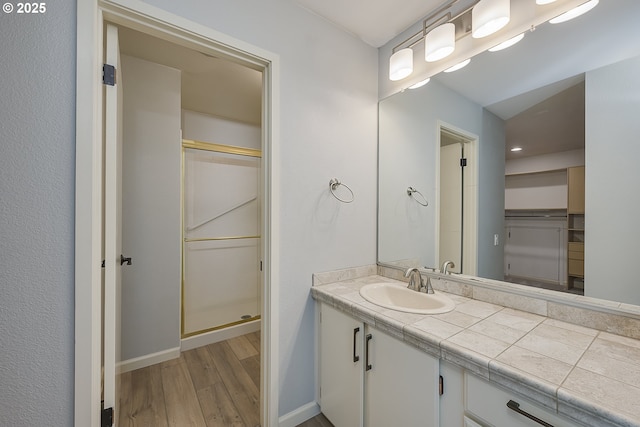 full bath featuring a shower stall, wood finished floors, vanity, and baseboards