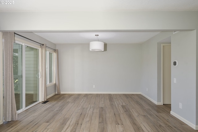 spare room featuring visible vents, baseboards, and wood finished floors