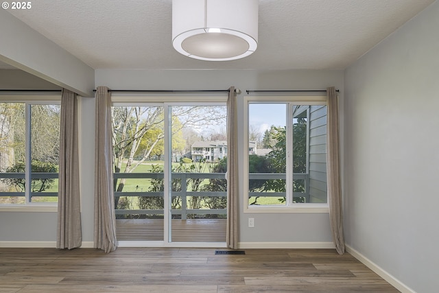 entryway featuring a textured ceiling, wood finished floors, and baseboards