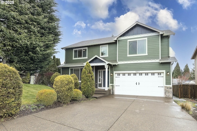 view of front of home featuring fence, concrete driveway, a garage, stone siding, and board and batten siding