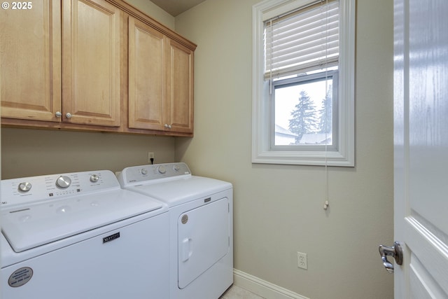 washroom with cabinet space, washing machine and dryer, and baseboards