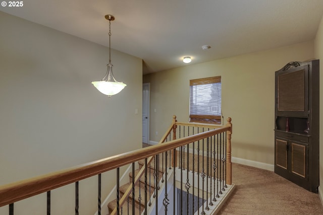 hall with an upstairs landing, baseboards, and light carpet