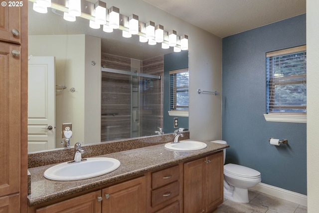 full bathroom with double vanity, a stall shower, toilet, and a sink