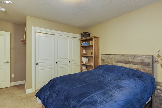 bedroom with a closet, carpet flooring, a textured ceiling, and baseboards