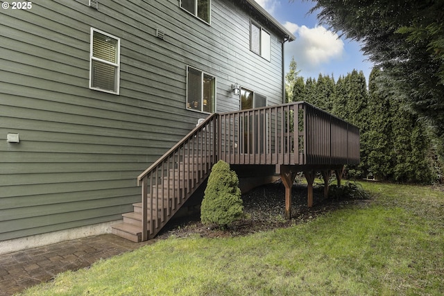 view of side of home with stairway, a lawn, and a deck