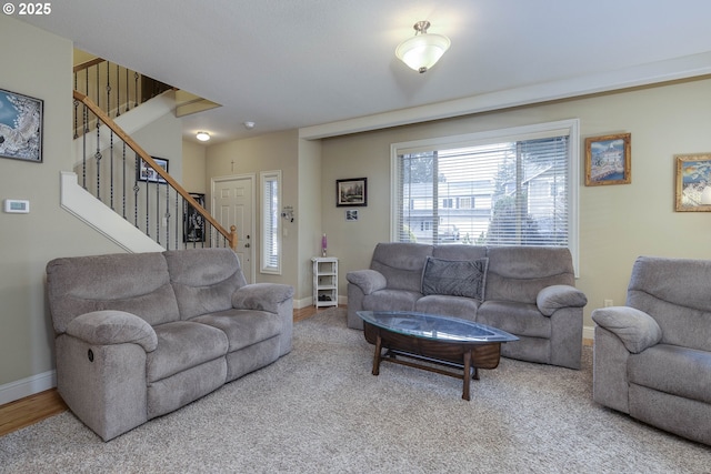 living area featuring baseboards and stairs