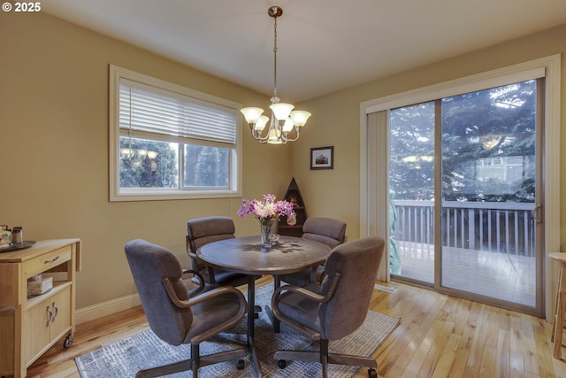 dining room with light wood finished floors, a notable chandelier, and baseboards