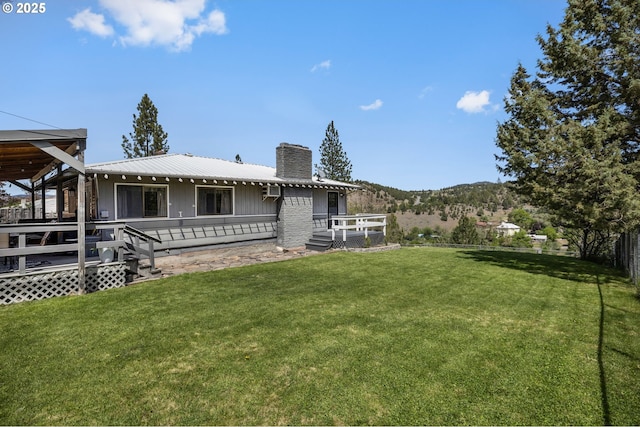 204 Adam Dr, Canyon City, OR 97820 - back of property with a chimney, a yard, a deck with mountain view, and metal roof
